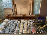 Assorted plastic ziplock bags of acrylic jewelry blanks and metal findings on table