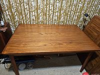 View of closed tabletop showing teak wood grain and tapered legs
