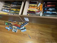Three wooden drawers filled with vintage Kibri plastic model trucks, some loose and many still in original packaging, displayed on a wooden floor.