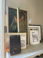 View of all framed and unframed prints arranged together alongside boxed brass photo frame.