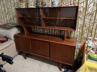 Front view of entire two-piece teak cabinet showing upper glass-door section and lower buffet base