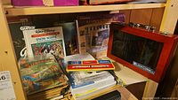 Vintage comics and art supplies on shelf including Disney Snow White book, Loew-Cornell pencil crayons in wooden box, painting kit, and assorted paper goods.