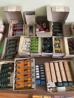 Top-down view of multiple open Wiking boxes on tabletop showing red panel vans at left, various tractors and trailers in center and top row