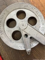 Close-up of metal clothesline pulley marked Wright Aluminum Co Limited Toronto, made in Canada, with integrated brake lever.
