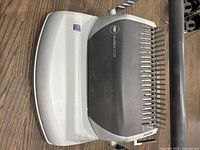 Top view of GBC CombBind C110 binding machine showing manual punching lever, punch pins and branding on machine surface.