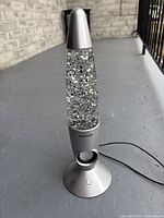 Front view of Craig Sparkle Rocket speaker showing metal base, clear glitter liquid chamber, and power button.