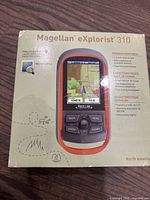 Photo of front of the box showing image of the Magellan eXplorist 310 device, highlighting color screen and physical buttons.