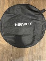 Black circular soft case with Neewer logo for carrying collapsible reflector or backdrop.