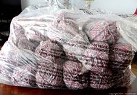 Large clear plastic bag filled with multiple balls of yarn showing the quantity and packaging