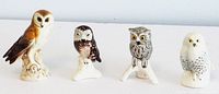 Four detailed Goebel ceramic owl figurines arranged in a row on a white surface with neutral background, showing front views of each owl.