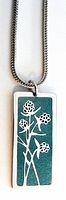 Close-up photo of the necklace pendant showing the floral inlaid design on a green background and silver outline.