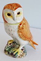 Front-right side view of barn owl figurine showing face and details of the painted feathers and base.