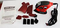 Full kit including Black & Decker Mouse sander, instruction manual, sanding papers, and attachments arranged on surface.