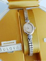 Side angle close-up showing watch face, band design, decorative stone element, and partial original box