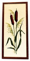 Full front view of framed needlepoint artwork showing bullrushes and leaves with wood frame.