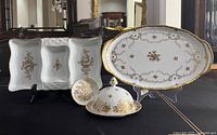 Photo showing all four porcelain serving pieces including the large oval tray, covered butter dish with dome lid, small round pin dish, and divided serving dish with gold gilding on white porcelain.