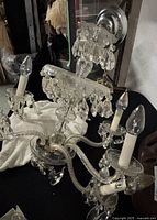 Full view of the chandelier angled showing multiple arms and some damage including broken arm and missing/prism chips.