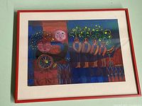 Framed painting showing colorful figures and a red frame on the wall.