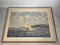 Full view of framed nautical print showing sailboats on wavy sea and distant hills under a cloudy sky, framed in light wood.