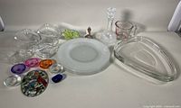 Full assortment of glass and crystal items on white surface showing warming plates, decanter, paperweight, sun-catcher, and various bowls and plates.