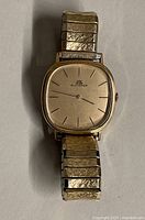 Front view of the vintage Bucherer watch showing gold tone face and stretch band.