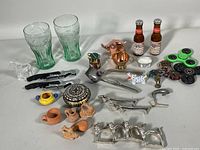 Full view of lot with various vintage collectibles including Coca-Cola glasses, miniatures, metal napkin rings, fidget spinners, and small bottles