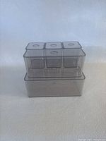 Front angle of all five acrylic storage containers stacked, showing their varying sizes and lids with round accents.