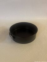 Small black springform pan with clasp shown from above to display shape and size.