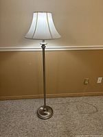 Full view of the floor lamp showing entire stand, base, and shade in a room environment.