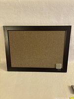 Full view of Quartet framed cork board against wall, showing medium size and black frame.