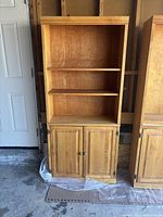 Front view of wooden bookcase showing three upper shelves and closed two-door cabinet below.