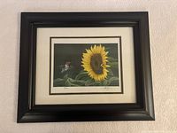 Framed print showing a sunflower with a hummingbird on leaves, black wide frame, cream matting.