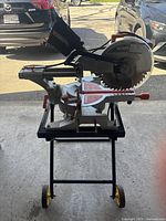 Front view of saw on mobile folding stand showing blade, housing and dust bag