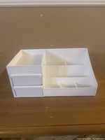 Image showing white plastic organizer with three small drawers on the left and multiple compartments for storage on the right.