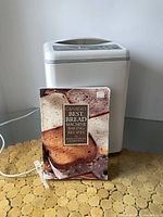 Front view of bread maker with the recipe book placed in front