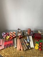 Overview of entire candle and holder lot displayed on glass top table with gold circular-patterned runner.