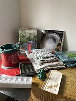 Photo of multiple Christmas items arranged including tree stands, tablecloths, napkins, napkin holder, place mats, plates, and small accessories