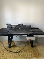 Full front view of the black Sears Craftsman router table standing on angled legs showing work surface and fence
