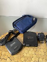 Photo showing both Sony Discman models (D-141 and Car Discman), carrying case, and accessories (power adapters and cables).
