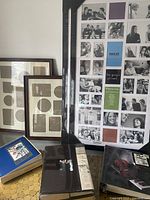 Various sized black photo frames with multiple photo openings, some still in plastic, alongside three unused retro photo albums with decorative covers.