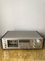 Front view of Sony TC-K61 cassette deck showing silver front panel and wooden sides on a tiled surface.
