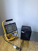 Work light and space heater together on a table showing the full view of both items including cords.