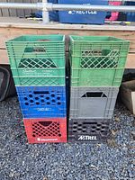 Front side view of stacked colorful vintage milk crates showing brand names and general condition