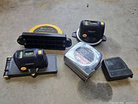 Three Mastercraft laser levels and one Craftsman measuring tape arranged on concrete floor showing condition and layout.