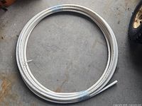 Coiled roll of white 1/2 inch diameter PEX plumbing pipe laid on concrete floor.