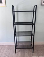 Front view of the 4-shelf steel shelf unit against a light-colored wall, showing all four shelves and overall structure.