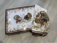 One placemat and the folded tea towel showing the turkey pattern and brown border.