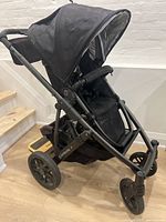 Side view of black Uppababy Vista stroller showing frame, wheels, canopy, and piggy back board attached