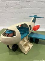 Front side view of the vintage airplane toy showing the open side door and pilot figure in cockpit.