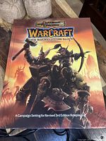 Front cover of the Warcraft RPG campaign setting book showing a battle scene with characters.